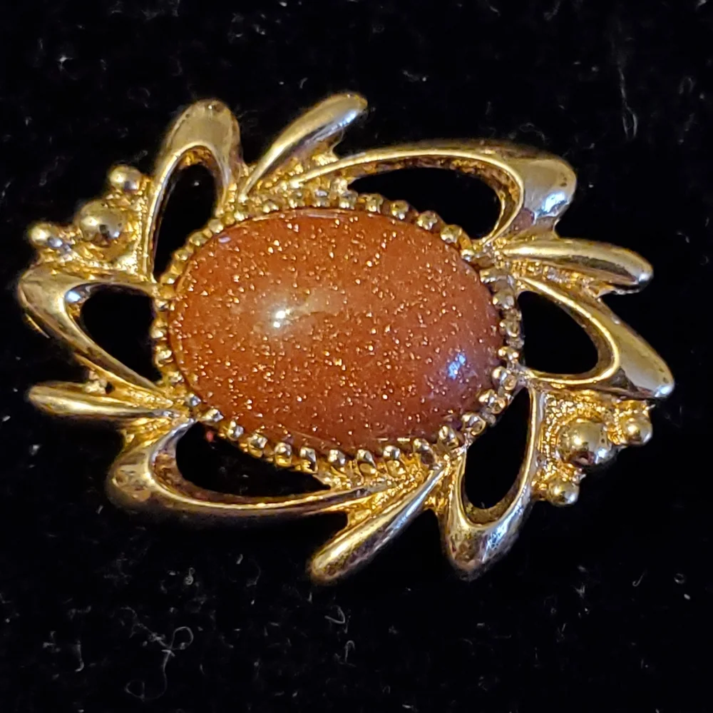 Goldtone brooch with rust colored glittery center stone